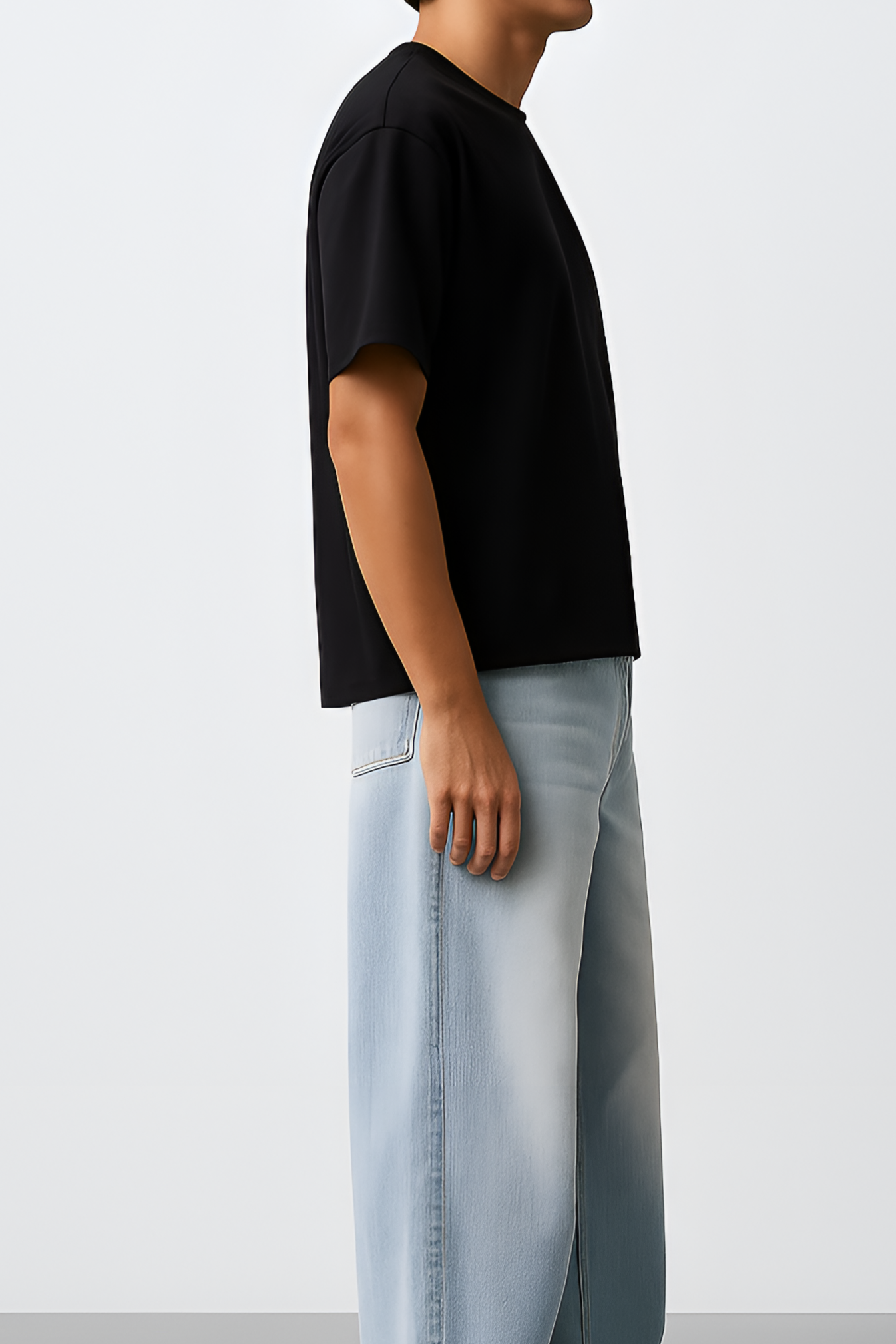 Person wearing a black t-shirt and light blue jeans standing against a white background